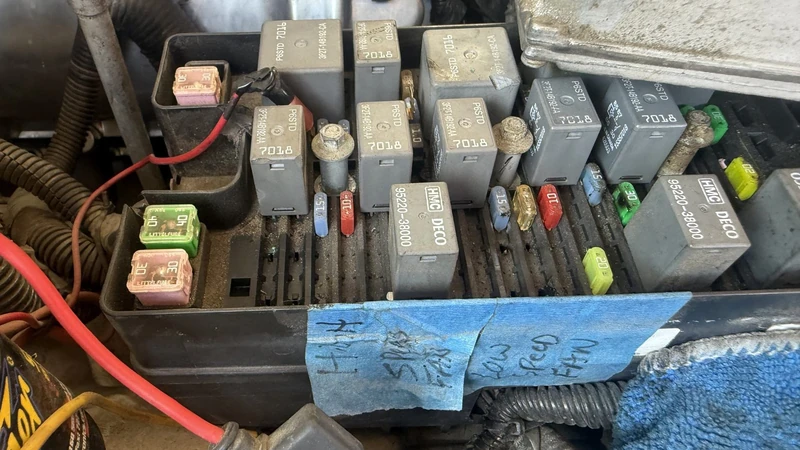 Fuse and relay box under the hood with labels on blue tape